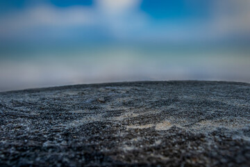 Close-up of weathered wood texture with blurred ocean and blue sky background, natural coastal scene