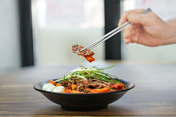 고기 국물 떡볶이를 젓가락으로 한 점 집은 모습을촬영하였습니다.