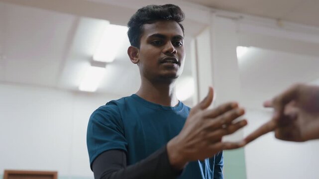 Brother in blue shirt playing hand trick indoors while opponent misses, bowing head in disappointment, showing emotion, challenge, and playful sibling competition