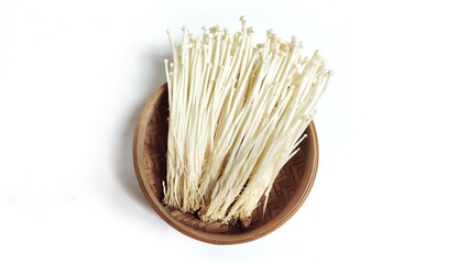 Top view of Fresh golden needle mushroom or Enoki in bamboo bowl isolated on white background. Enokitake (Flammulina velutipes) from asian cuisine. Delicious for soups and stir-fries cuisine.