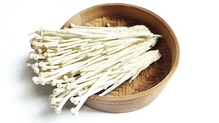 Close up of Fresh golden needle mushroom or Enoki in bamboo bowl isolated on white background. Enokitake (Flammulina velutipes) from asian cuisine. Delicious for soups and stir-fries cuisine.
