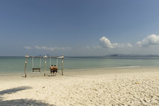 Gay couple in a swing on the beach of Koh Mook Island, Andaman Sea, Satun Province, Southern Thailand, Thailand