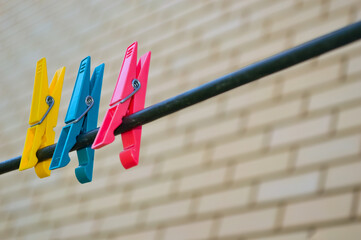 three clothespins are attached on a clothesline - pink, blue, yellow