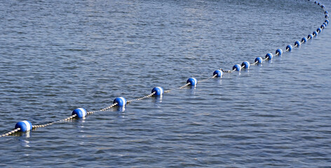 String of Buoys placed on surface of blue lake waters creating a safety boundary for swimmers
