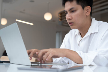 Serious man concentrating on laptop work in modern office, representing digital business, remote work, online communication, freelance career, productivity, and professional workplace lifestyle.