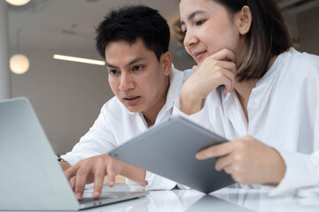 Man and woman working together with laptop and tablet in modern office, representing teamwork, startup collaboration, digital project planning, online communication, and business productivity.
