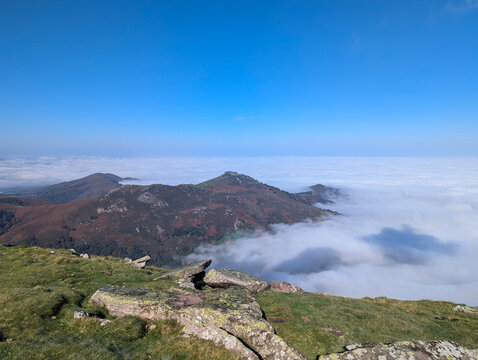 Esplendor outonal do cume de Artzamendi em Itxassou com montanhas emergindo de um mar de nuvens brancas de neblina Sob um c&eacute;u azul