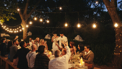 Romantic outdoor wedding reception under twinkling string lights surrounded by loved ones