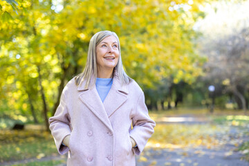 Mature woman enjoying autumn walk in nature park