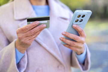 Senior woman holding credit card and smartphone for online payment