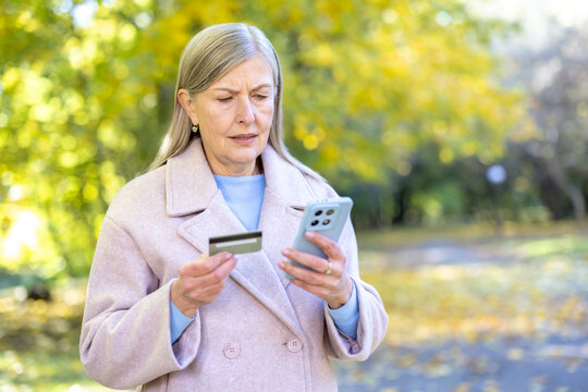 Senior woman feeling confused holding credit card and phone