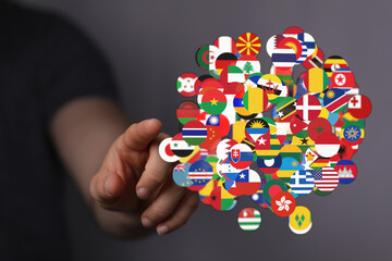 A person's hand surrounded by numerous international flags symbolizes global cooperation, cultural exchange and international relations. Represe