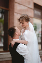 Happy, sensual newlyweds embrace. A happy bride and stylish groom hold hands and stroll through the city.