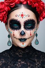 Halloween beauty close-up portrait of woman looking down. Female adorned with Santa Muerte makeup.