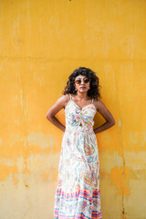 Fototapeta premium A woman in a white dress stands in front of a yellow wall