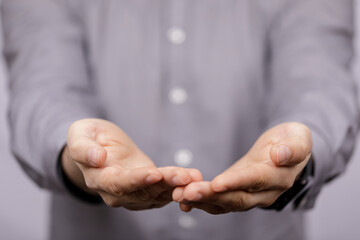 Obraz premium Close-up view of a man's hands, palms open, suggesting giving or receiving something. Concept of help, offering, or asking. Neutral background.