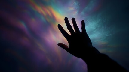 A silhouetted hand reaches out into a swirling vortex of vibrant multicolored light patterns