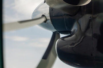 Close-up view of an airplane turboprop engine and propeller blades during flight. Aviation background with metallic textures and engineering details.