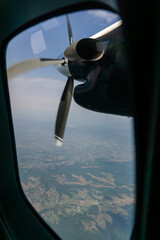 Airplane Propeller and Landscape View from Window. View of an aircraft propeller in motion seen from the passenger window. Aerial landscape with farmlands and hills visible below on a clear day.