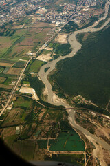 Aerial View of Farmland and Mountains in Summer. Aerial view of agricultural fields and rural landscape surrounded by green mountains. A patchwork of farmland with small villages and under a hazy sky.
