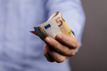 A person holding a 50 Euro banknote in their hand. Financial concept, saving, and investment....
