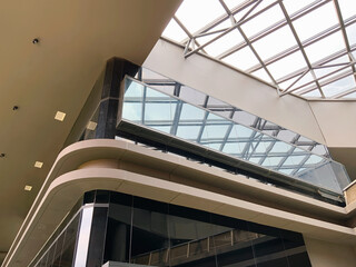 Stunning modern architecture with a sleek glass facade and expansive skylight, reflecting urban...