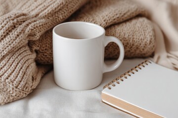 A cozy scene with a white mug, knitted fabric, and a minimalist notebook