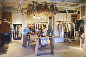 Wide view of two young women shopping in stylish boutique