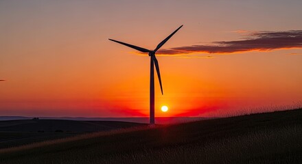 Obraz premium A wind turbine stands tall against a vibrant sunset sky, casting a silhouette against the fiery orange and pink hues of the setting sun.