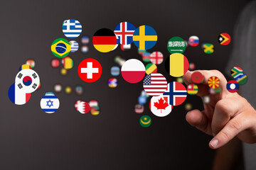 A person's hand interacting with a display of global flags representing diverse nations and international connections. Symbol of travel, culture