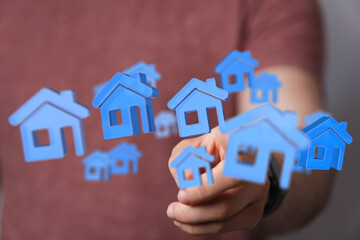 Hand holding and offering 3D blue house icons. Representing concept of home ownership, dream house, family, mortgage, real estate, and investmen