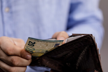 Close-up of a person holding a wallet with Euro banknotes, representing concepts of finance, money,...