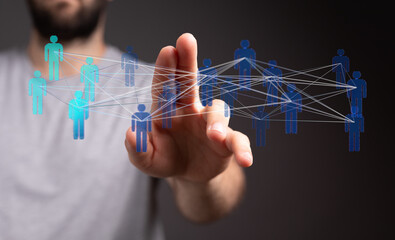 Hand reaching towards a network of connected human figures, representing digital networking, communication, teamwork and business.