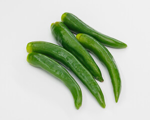 A group of fresh green chili peppers arranged on a clean white surface. Bright, glossy skins suggest crisp, flavorful ingredients ready to spice up sauces, salsas, stews, or healthy dishes