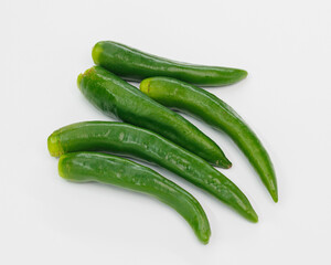 A group of fresh green chili peppers arranged on a clean white surface. Bright, glossy skins suggest crisp, flavorful ingredients ready to spice up sauces, salsas, stews, or healthy dishes