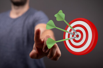 Close-up of a person's finger pointing at a dartboard with three darts hitting the center....