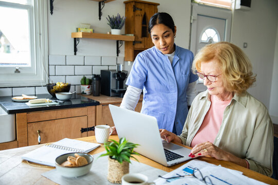Senior woman with caregiver reviewing bills and finances at home