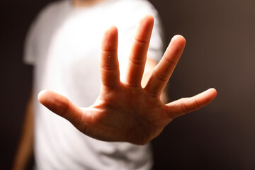 Obraz premium Close up of a hand reaching out, showcasing an open palm, often interpreted as a stop gesture or a gesture of refusal, showing the concept of st