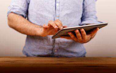 A man using a tablet, fingers touching the screen, with a blurred background, business or work theme, modern technology.