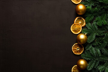 Black background with magnificent fir branches and golden christmas balls. Shot from above. Christmas mood background.