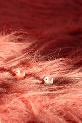 Two small toy ducks nestled in a fluffy, soft, textured pink fabric resembling fur at daytime