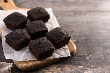 Homemade chocolate brownies with sugar powder on wooden table. Copy space