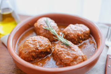 Tuna rolls in tomato sauce served on clay plate with rosemary and olive oil, rustic homemade food horizontal composition.