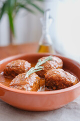 Tuna rolls served on clay plate with olive oil bottle and yucca plant in background. Vertical composition with copy space