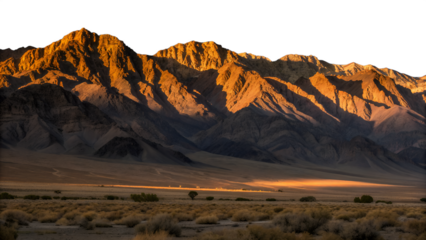 An isolated mountain range glows with golden sunrise light, casting long shadows across the vast, rugged desert landscape.