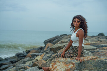 A woman is sitting on a rock by the ocean
