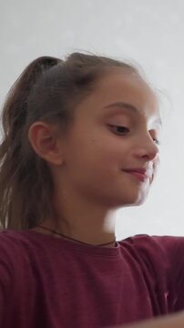 boy writing with warm smile while sister in maroon top gently slaps his head playfully and continues her activity as both share lighthearted moment in cozy home setting with visible affection