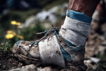 Close-up of a muddy athletic shoe worn by a hiker on a rugged trail, showcasing the wear and tear of outdoor adventures and the connection to nature