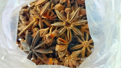 A charming close-up of a number of dried star anise flowers, beautifully scattered inside a plastic bag.