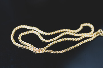 A shiny gold necklace on a black background